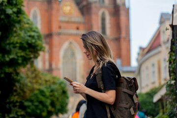 young girl with a smartphone on the background of the old church in Europe