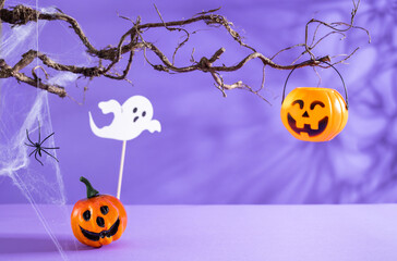 Halloween decorations with pumpkins, spider, spider web, ghost and bat on purple background. Halloween party concept.