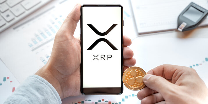 Russia Moscow 24.06.21 Logo of Ripple coin in mobile phone. Cryptocurrency XRP token. Trading blockchain platform to buy,sell on decentralized exchange DEX. Digital money.Business,investing