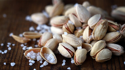 Pistachios with sea salt on a wooden surface.