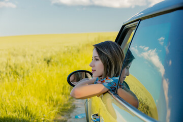 young girl in a car on green wheat field