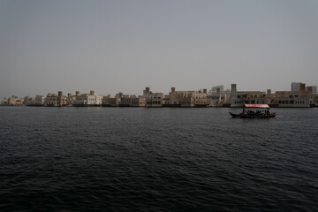 small boat on a river in dubai with lots of small houses in the background