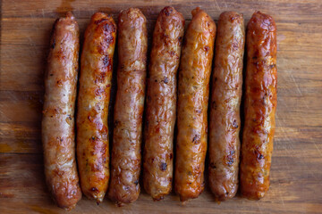 Seven appetizing toasted sausages with turkey lie on a wooden board