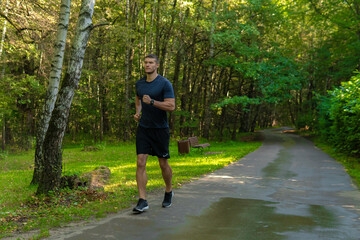 A man athlete runs in the park outdoors, around the forest, oak trees green grass young enduring athletic athlete active sport forest, workout outdoor young male, trees Autumn leisure cross, distance