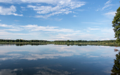 Fototapeta na wymiar Blue sky covered with white clouds and sky reflection in the calm water of Pilka lake