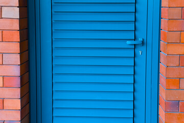 Photo of a blue painted wooden door on a red brick wall.