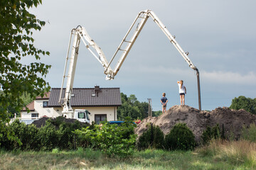 children watch concrete pouring from a truck concrete mixer to the foundation of a new house