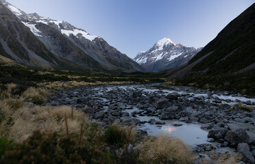 Naklejka na ściany i meble photo of mt cook in new zealand with a river in the foreground.