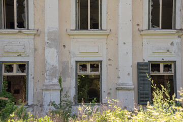 Damaged wall with broken windows and bullet holes. Abandoned tourist resort in Kupari, Croatia. 