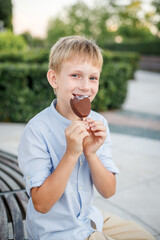 blonde boy in blue shirt eating popsicle ice cream