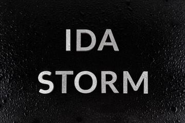 the words ida storm laid with silver metal letters over black surface both covered with rain water...