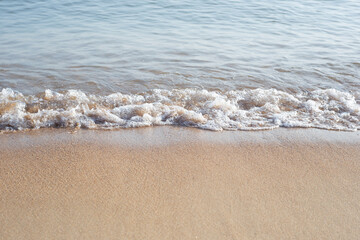The neutral background of the sea surf. The wave hits the sand with bubbling foam