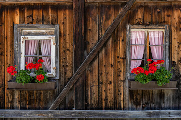 Fototapeta na wymiar Blumenkästen an einem alten Haus aus Holz in Östereich im Defereggental, Tirol
