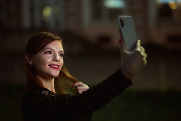 Sensual young woman taking selfie in the night city