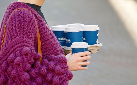 Woman hold in hands paper container with hot coffee cups Lavazza, coffee to go. Woman holding in hand paper cups Lavazza in city street, takeaway coffee in female hands closeup.