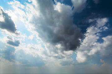 Obraz premium Amazing white fluffy clouds moving across the sky in bright sunshine. Beautiful sun rays shine through the clouds creating heavenly and peaceful atmosphere.