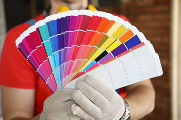 A man in gloves shows color swatches for repair