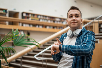 Looks at the time on the smart watch. The student studies literature in the library at the college. Academic year at the Institute.