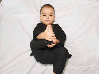 A little Baby Boy laying down and play with his Foot