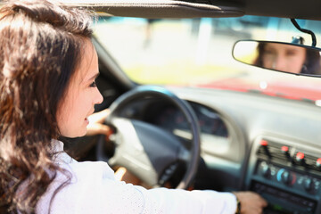Plakat Young brunette woman sits behind the wheel of car