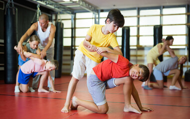 Two preteen boys in pair practicing self-protection during group class at gym