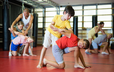Obraz premium Two preteen boys in pair practicing self-protection during group class at gym