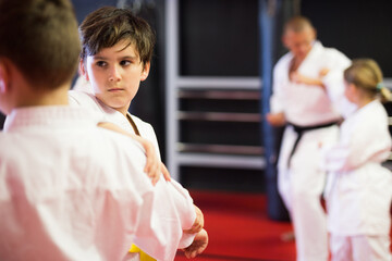 Karate kids in kimono sparring together during their group karate training.