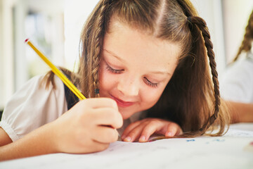 Young spanish girl writing on notebook with pencil at class