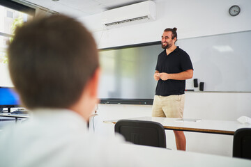 Cheerful teacher laughing while doing the lesson - obrazy, fototapety, plakaty
