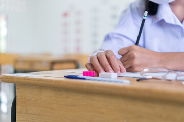 Girl Student in exam test school, Side View of high school or university holding writing document paper answer sheet and lecture final exams in classroom with white uniform pupil of Thailand