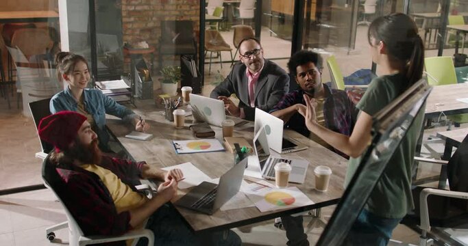 Team of multiethnic millennial creative businesspeople doing a highfive while brainstorming on marketing customer orientation strategy - business success 4k footage