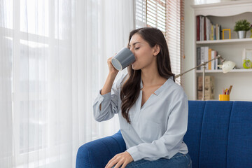 Young caucasian woman sitting sofa enjoying first morning coffee.