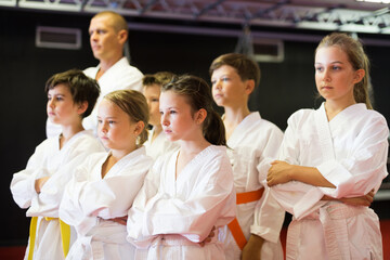 Fototapeta na wymiar Portrait of focused preteen kids posing before training at karate class indoor
