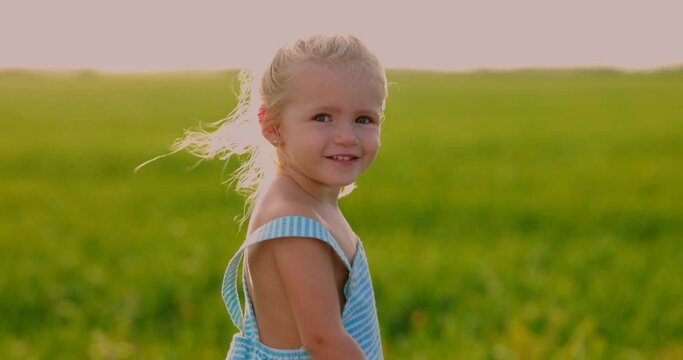 Plano medio de ni&ntilde;a sonriendo al atardecer en el campo. C&aacute;mara lenta.