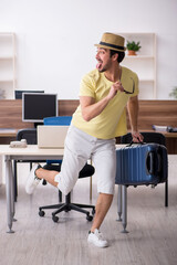 Young male employee preparing for trip at workplace