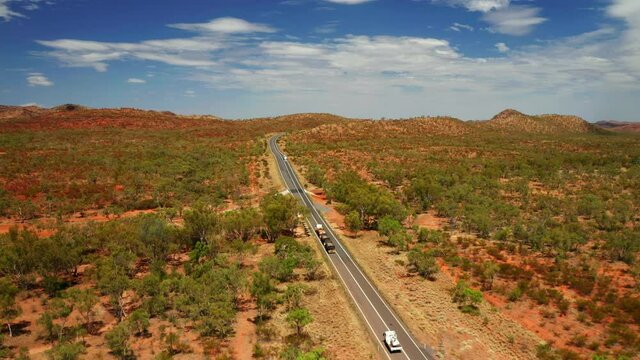 Trucks And Vehicle Driving Across Highway Passing Through Bushland In Outback, Northern Territory, Australia. - Aerial Tracking