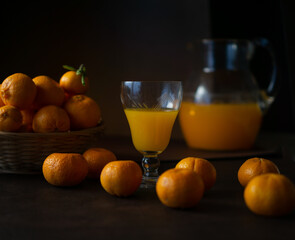 glass with orange juice (oranges and tangerines in the background)