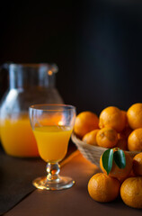 glass with orange juice (oranges and tangerines in the background)