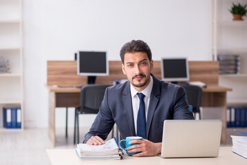 Fototapeta premium Young male employee drinking coffee during break