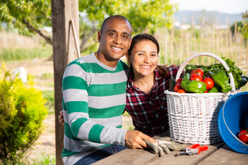 Happy married couple resting at rustic table after harvesting vegetables