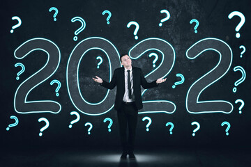 Fototapeta na wymiar Businessman with question marks and 2022 numbers