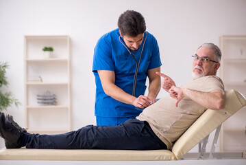 Obraz premium Old male patient visting young male doctor