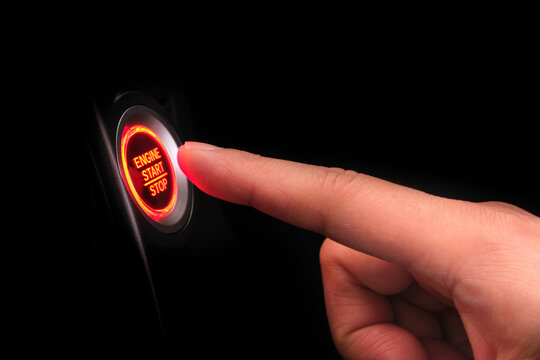 The driver's hand is pressing the car start button. Concept of transportation and technology