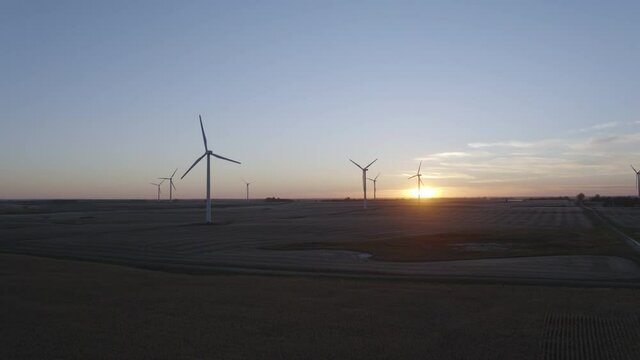 Aerial view of wind power turbines spinning in the twilight of sunset, spring in the USA - rising drone shot