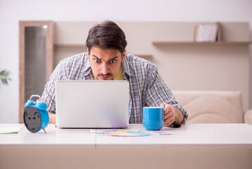 Young male freelancer in time management concept at home