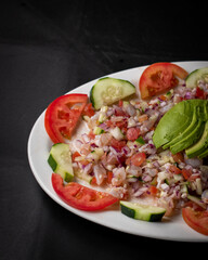 Fish and shrimp ceviche dish with avocado, tomato and onion, Mexican