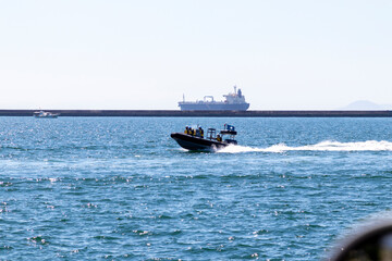 疾走するゴムボートと貨物船