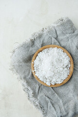 coarse rock salt on a wooden plate on a coarse gray napkin. vertical, selective focus