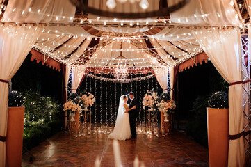 the bride and groom on the night street among the garlands