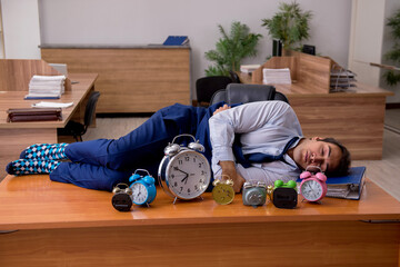 Young male employee sleeping in the office in time management co